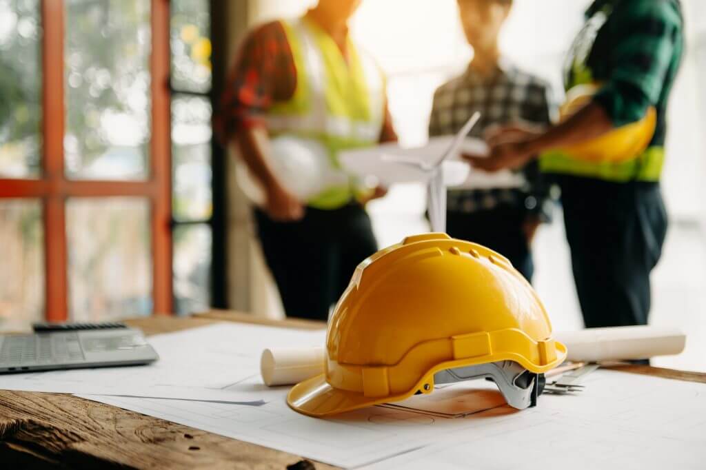 Hard hat on a table with contractors in the background.